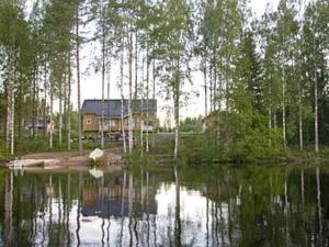 a house on the shore of a lake with trees at Holiday Home Mielikki by Interhome in Kurkimaki