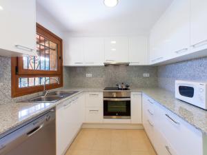 uma cozinha com armários brancos, um lavatório e um micro-ondas em Holiday Home Sansu by Interhome em Calonge