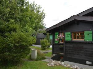 ein schwarzes Haus mit grünen Türen und einem Fenster in der Unterkunft Apartment Ismene- Chalet by Interhome in Gstaad