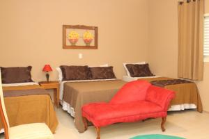 Pousada Sítio Pedras de Minas في مونتي سيو: غرفة نوم بسريرين وكرسي احمر