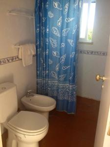 a bathroom with a toilet and a blue shower curtain at Cozy Country House near Beaches in Azoia