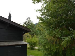 Ein schwarzes Haus auf einem Feld mit einem Baum in der Unterkunft Apartment Ismene- Chalet by Interhome in Gstaad