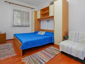 a small bedroom with a blue bed and a couch at Apartment Dijana-2 by Interhome in Prigradica
