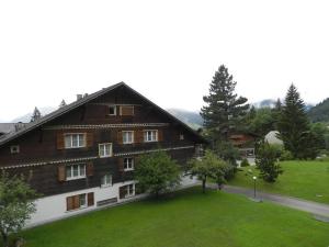 a large wooden house with a green lawn in front of it at Apartment Suzanne Nr- 20 by Interhome in Gstaad