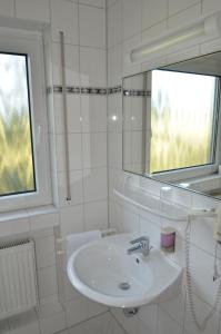 a white bathroom with a sink and a mirror at Landhotel Sulzbacher Hof in Frankfurt/Main