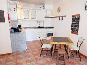 a kitchen with white cabinets and a table and chairs at Studio Studio Ericeira by Interhome in Ericeira
