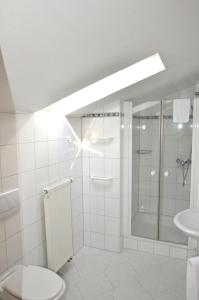 a white bathroom with a shower and a toilet at Landhotel Sulzbacher Hof in Frankfurt/Main