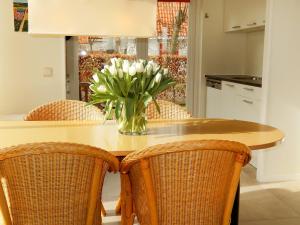 een vaas met bloemen op een tafel met stoelen bij Holiday Home Stern Comfort by Interhome in Noordwijk