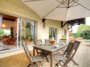 a wooden table with chairs and an umbrella on a patio at Holiday Home Bernadon by Interhome in Labenne