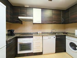 a kitchen with white appliances and wooden cabinets at Apartment Can Pavet by Interhome in Vilafortuny