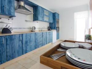 eine Küche mit blauen Schränken und einem Tisch mit Tellern darauf in der Unterkunft Holiday Home Pelzer by Interhome in Conil