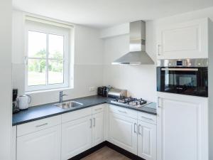 Una cocina con gabinetes blancos y un fregadero y una ventana. en Holiday Home Alk 8-1 by Interhome, en Noordwijkerhout