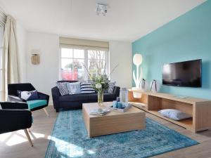 een woonkamer met een bank en een tv bij Holiday Home de Witte Raaf-1 by Interhome in Noordwijk