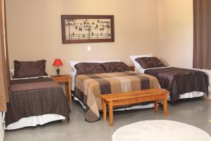 Habitación de hotel con 2 camas y mesa en Pousada Sítio Pedras de Minas en Monte Sião