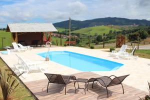 a swimming pool with chairs and a table at Pousada Sítio Pedras de Minas in Monte Sião