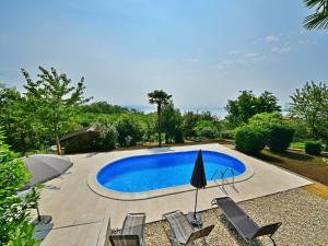 einen Pool in einem Garten mit Stühlen und einem Sonnenschirm in der Unterkunft Apartment Zvonko-1 by Interhome in Lovran