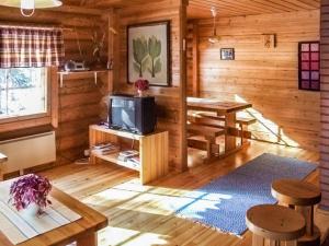 a living room of a log cabin with a tv and a table at Holiday Home Kujalan lomat 1 by Interhome in Nissi
