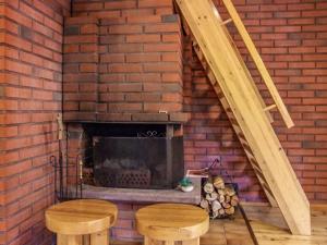 a brick fireplace with two wooden stools in front of it at Holiday Home Kujalan lomat 1 by Interhome in Nissi