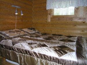 a bed in a log cabin with a window at Holiday Home Mökinniemi by Interhome in Soiniemi