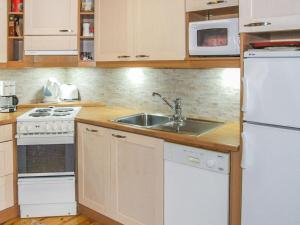 a kitchen with a sink and a white refrigerator at Holiday Home Kujalan lomat 2 by Interhome in Nissi