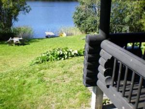 a bench sitting in the grass next to a lake at Holiday Home 6144 by Interhome in Jäniskylä