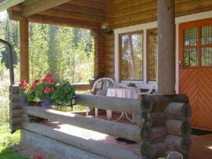 un porche de una cabaña de madera con mesa y sillas en Holiday Home Kettupirtti by Interhome, en Soiniemi
