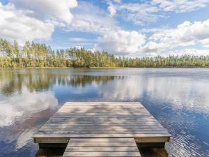 a dock on a lake with trees in the background at Holiday Home Valkealammi by Interhome in Vehmainen