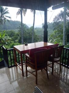TirtaganggaにあるPondok Alam Bukitの木製テーブルと椅子付きのバルコニーから眺めの良い景色を楽しめます。