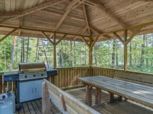 a wooden porch with a picnic table and a grill at Holiday Home Valkealammi by Interhome in Vehmainen