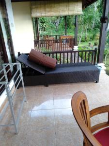 a porch with a bench and a table and chairs at Pondok Alam Bukit in Tirtagangga