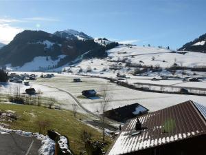 a snow covered hill with houses and a mountain at Apartment Fabiana by Interhome in Zweisimmen