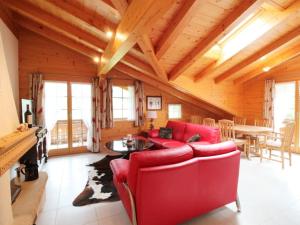 un soggiorno con divano rosso e tavolo di Apartment Farfalla by Interhome a Gstaad