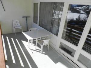 d'un balcon avec une table blanche et deux chaises. dans l'établissement Apartment La Sarine 222 by Interhome, à Gstaad