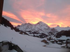 a sunset over a snow covered mountain with a village at Apartment Abelied by Interhome in Adelboden