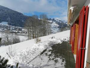 a snow covered sidewalk next to a building with red doors at Apartment Schön-Egg by Interhome in Zweisimmen