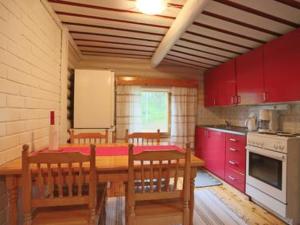 a kitchen with a wooden table and red cabinets at Holiday Home Ravelin by Interhome in Ylläsjärvi