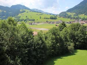 een uitzicht op een groen veld met bomen en bergen bij Apartment Schön-Egg by Interhome in Zweisimmen