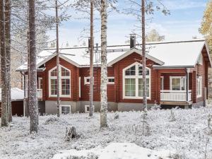 a wooden house in the snow with trees at Holiday Home Poronpurema a by Interhome in Levi