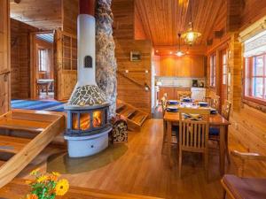 a kitchen and dining room with a fireplace in a log cabin at Holiday Home Riutankolo by Interhome in Lipinlahti