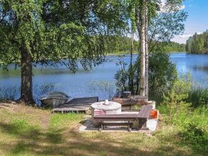 ein Picknicktisch und Bänke neben einem See in der Unterkunft Holiday Home 21 by Interhome in Varparanta