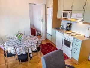uma cozinha com uma mesa com cadeiras e uma cozinha com electrodomésticos brancos em Holiday Home Point vale 4 ap-3 by Interhome em Tahkovuori