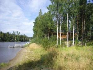 une cabine sur la rive d'un lac avec des arbres dans l'établissement Holiday Home Grande tahko by Interhome, à Valkeinen