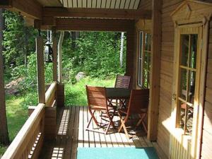 a porch of a cabin with two chairs and a table at Holiday Home Mustikka by Interhome in Röylä