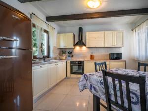 een keuken met witte kasten, een tafel en een koelkast bij Holiday Home Dorijano by Interhome in Ripenda Kras