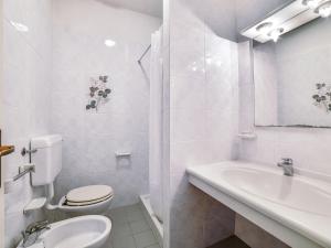 a white bathroom with a toilet and a sink at Apartment Altaluna-5 by Interhome in Nisporto +12 photos