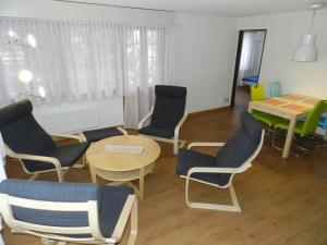 ein Wohnzimmer mit Stühlen, einem Tisch und einem Tisch in der Unterkunft Apartment Diana by Interhome in Gstaad