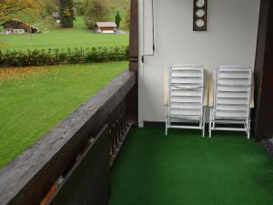 グスタードにあるApartment Oberland Nr- 29 by Interhomeの緑の芝生のポーチに座る椅子2脚