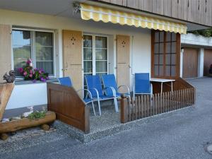 eine Veranda mit blauen Stühlen und einem Tisch auf einem Haus in der Unterkunft Apartment Eichhorn by Interhome in Zweisimmen