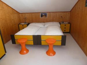 a bedroom with a bed and two orange stools at Apartment Berg by Interhome in Engelberg