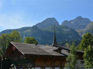 a building with a church with mountains in the background at Apartment Mittaghorn by Interhome in Gsteig